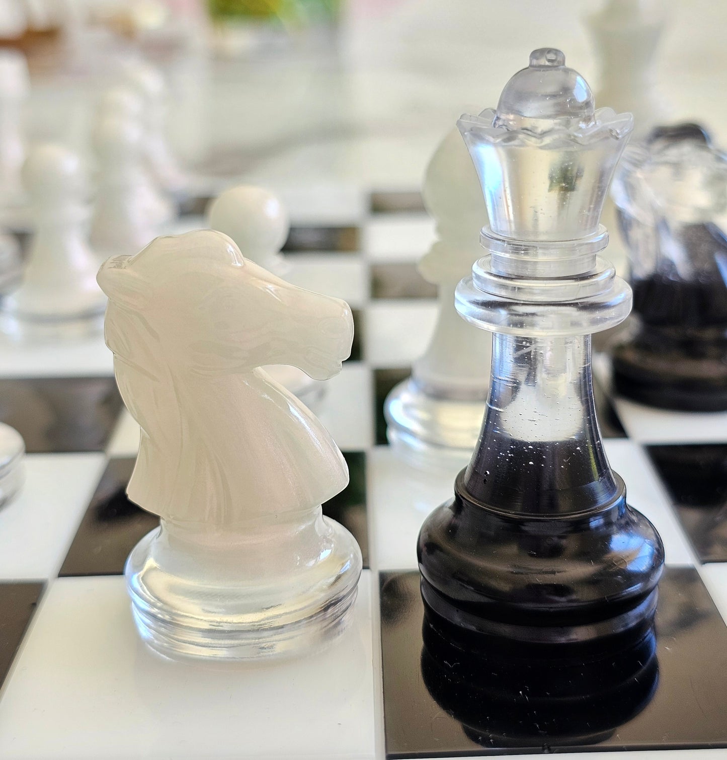 Artistic resin chess pieces in various colors on game board