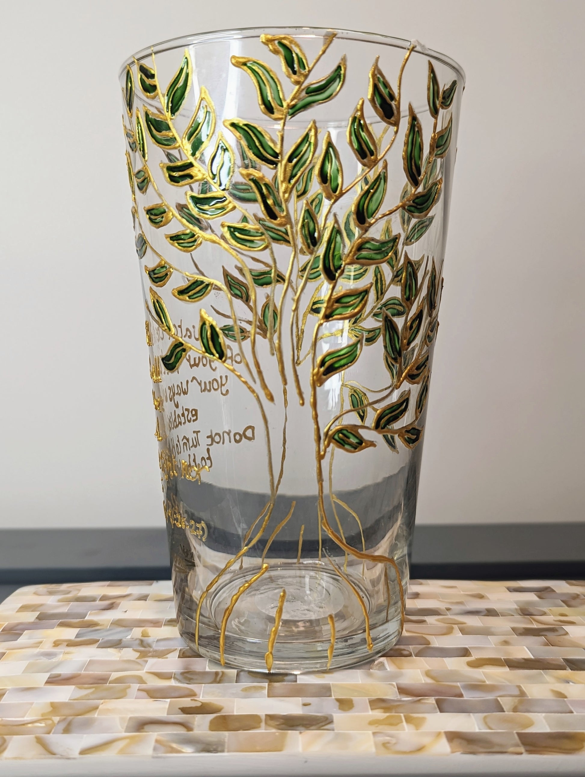 Personalised hand-painted glass vase with green and gold leavesThis hand-painted glass vase features a unique green and gold leaves and tree design, making it a 100% original piece of art. Each vase is hand-painted, ensuring no two are alike. Make it even