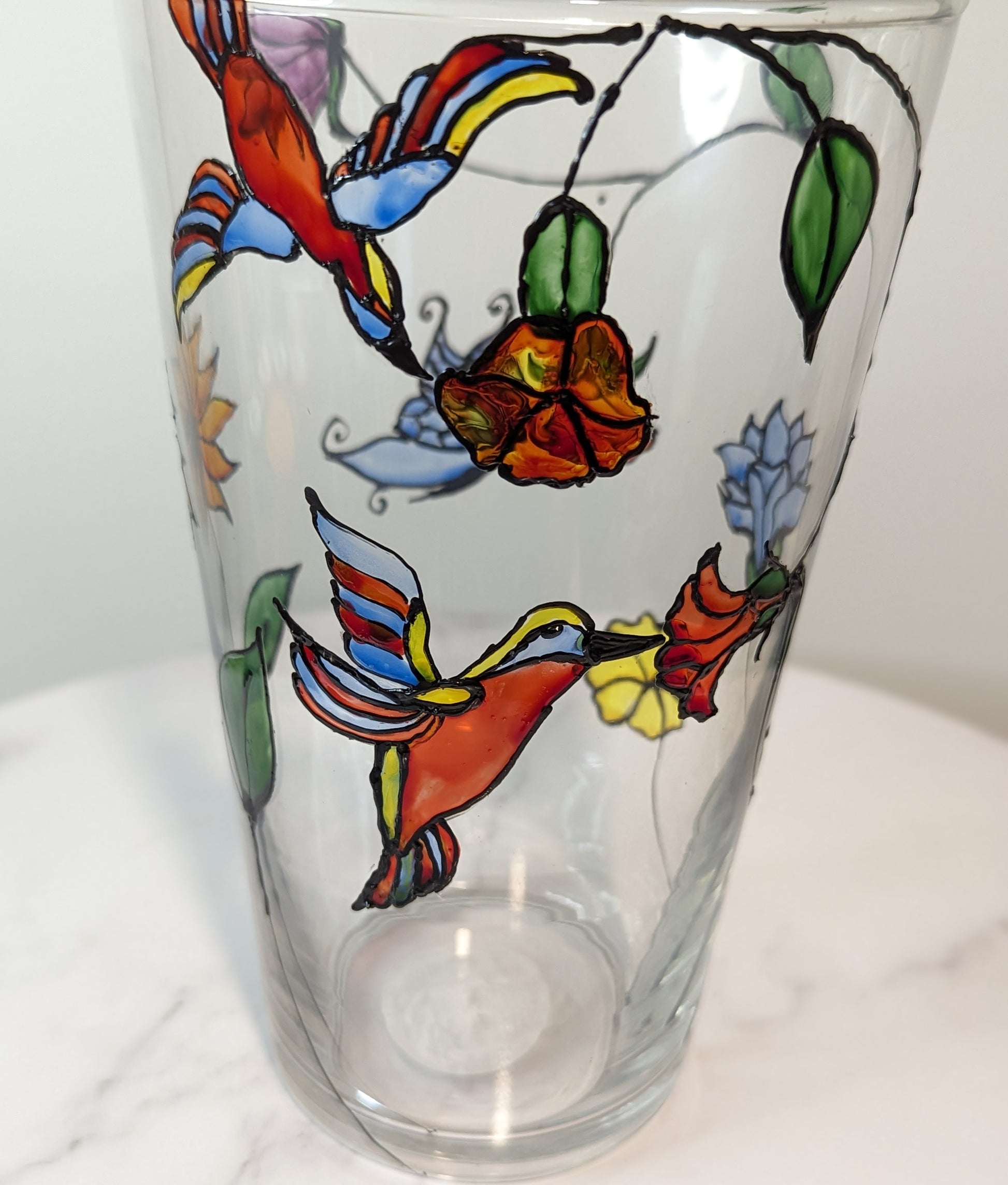 Personalised hand-painted glass vase with colourful parrots, flowers and butterflies.This hand-painted glass vase features a unique depiction of flying parrots surrounded by vibrant flowers and butterflies, capturing the essence of colourful nature and jo