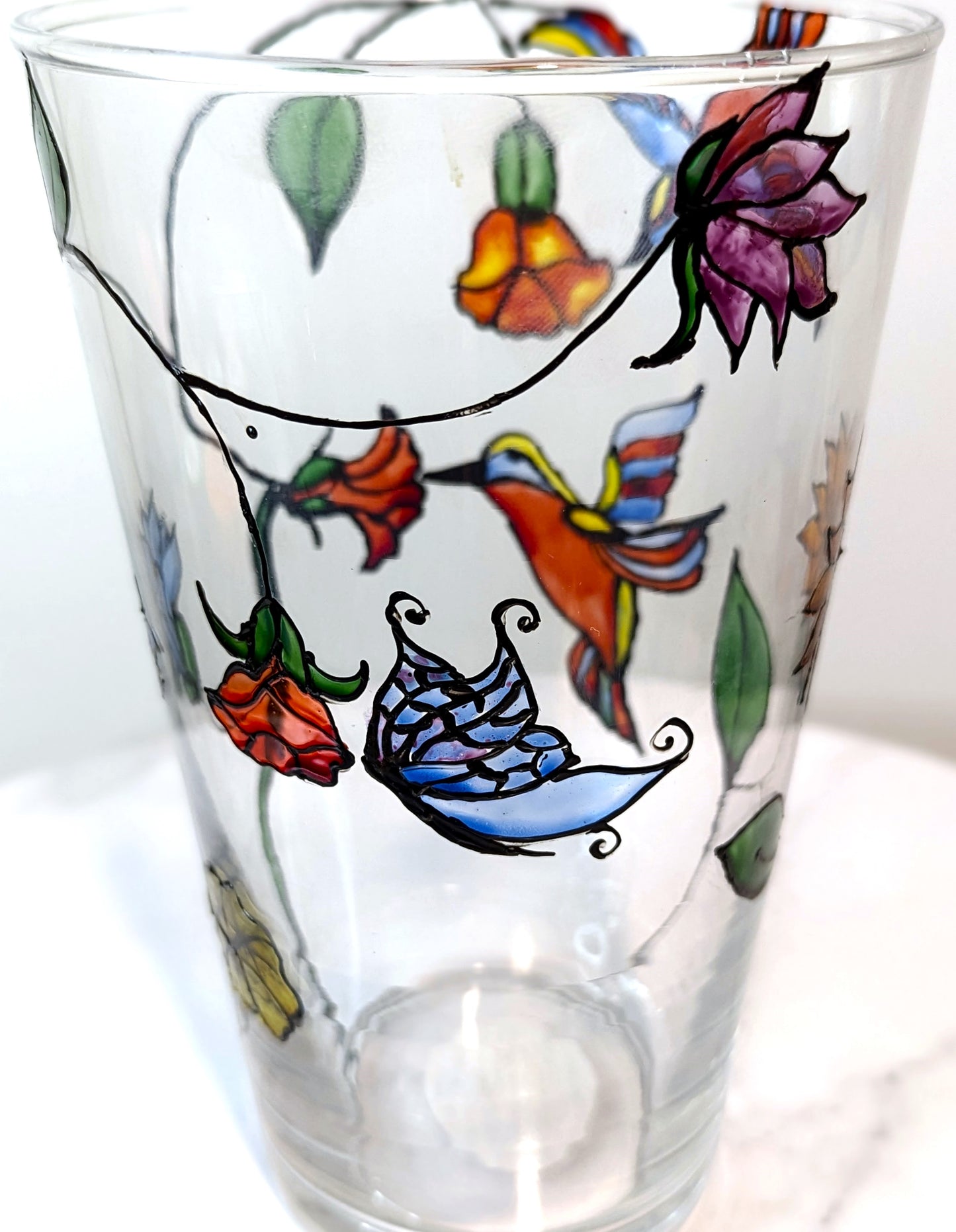 Personalised hand-painted glass vase with colourful parrots, flowers and butterflies.This hand-painted glass vase features a unique depiction of flying parrots surrounded by vibrant flowers and butterflies, capturing the essence of colourful nature and jo